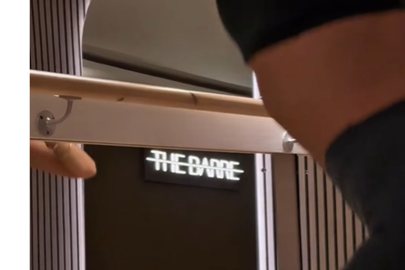 The Barre neon sign glowing above the studio's wooden barre